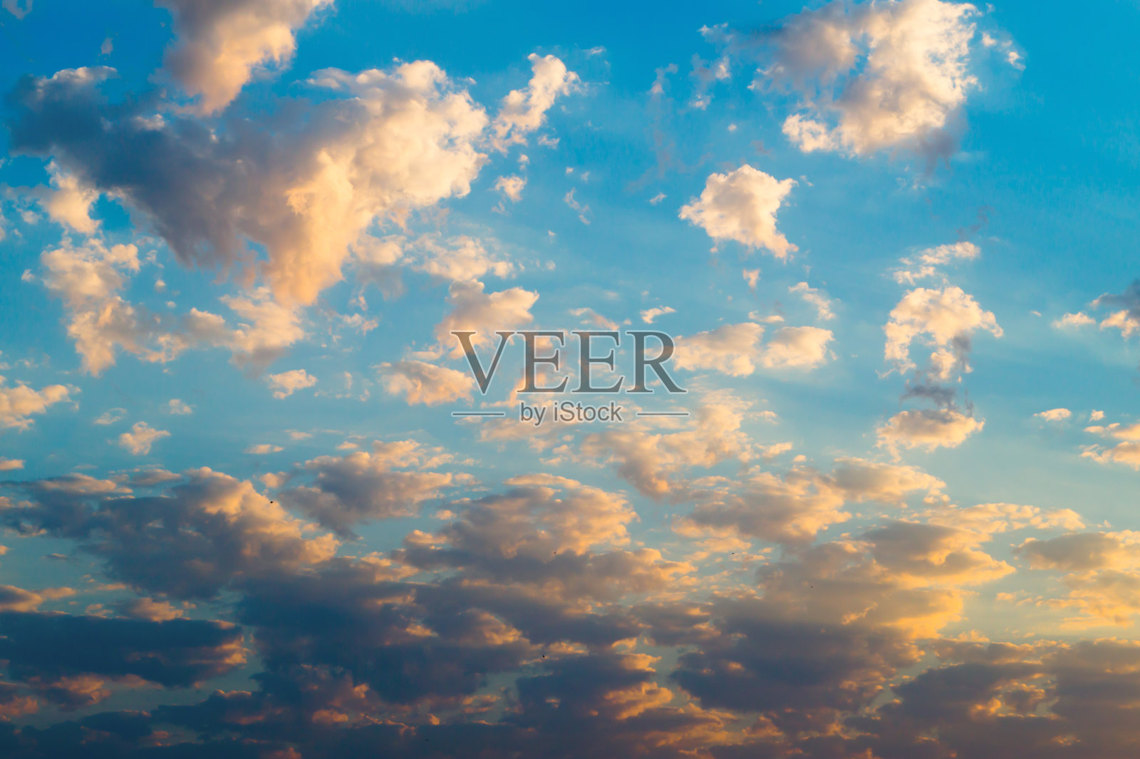 在日落或日出时，蓝色的天空上有明亮的黄色和黑色的云照片摄影图片