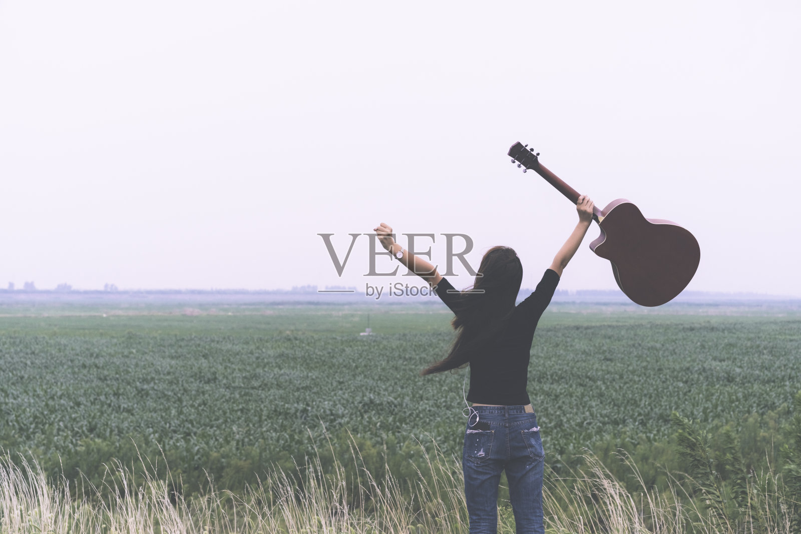 年轻女子拿着吉他在天空中行走照片摄影图片