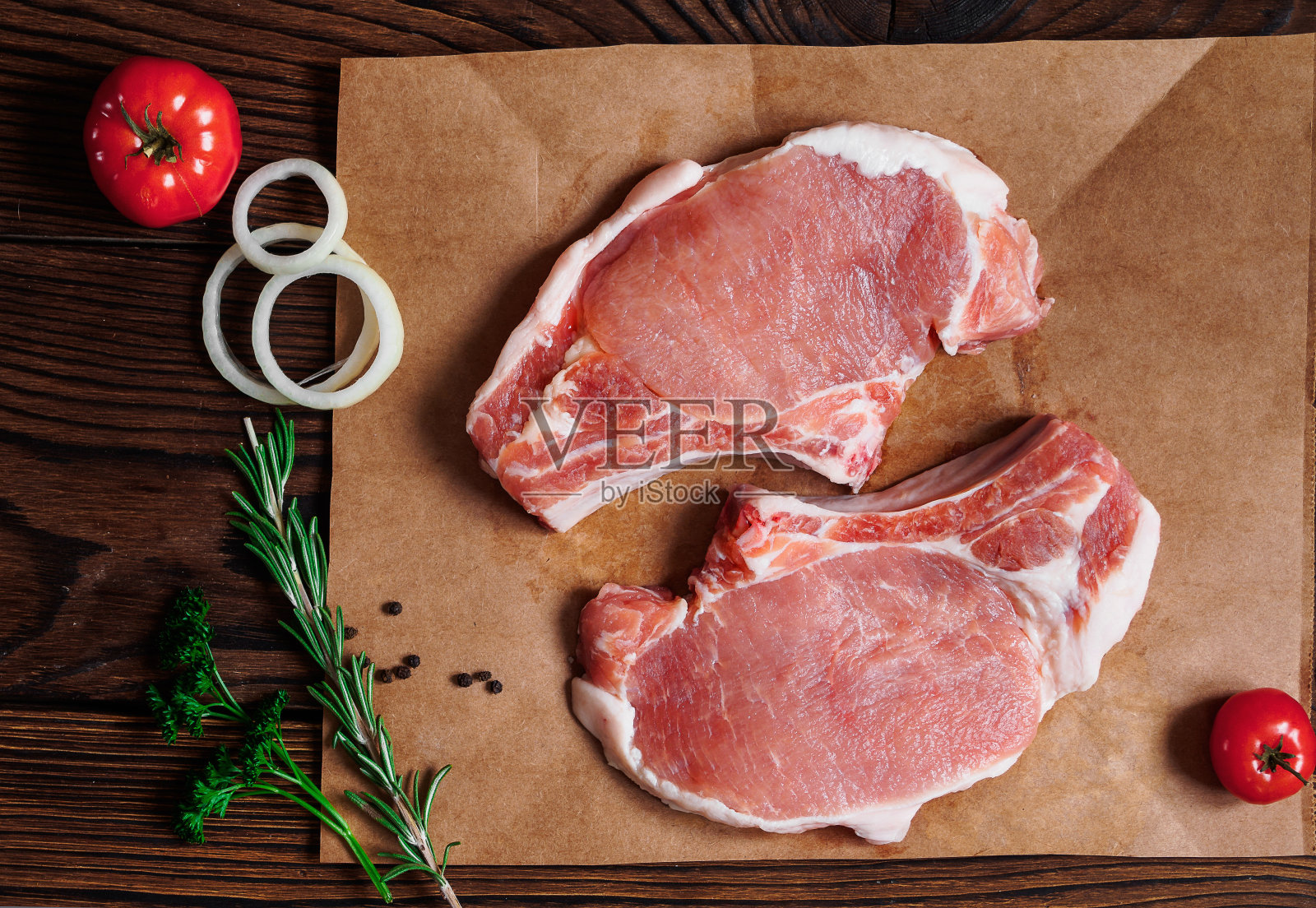新鲜的生猪肉在牛皮纸上，木制的背景照片摄影图片