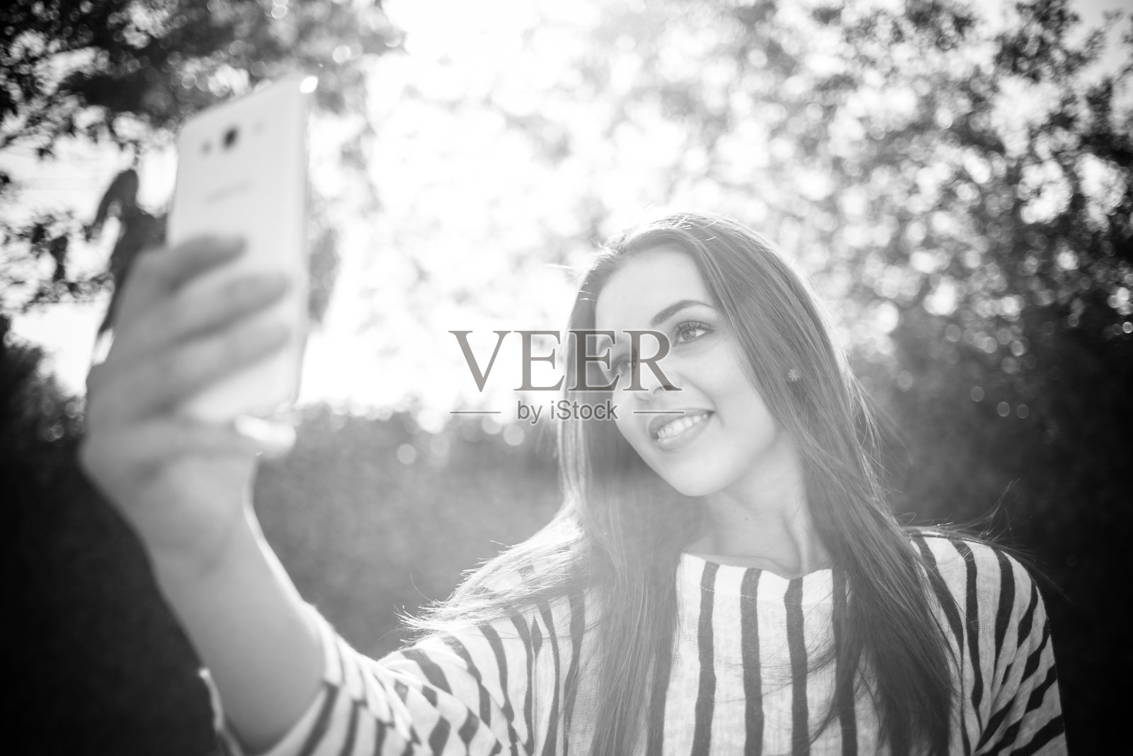 黑发女商人用她的智能手机工作、聊天和发短信。照片摄影图片