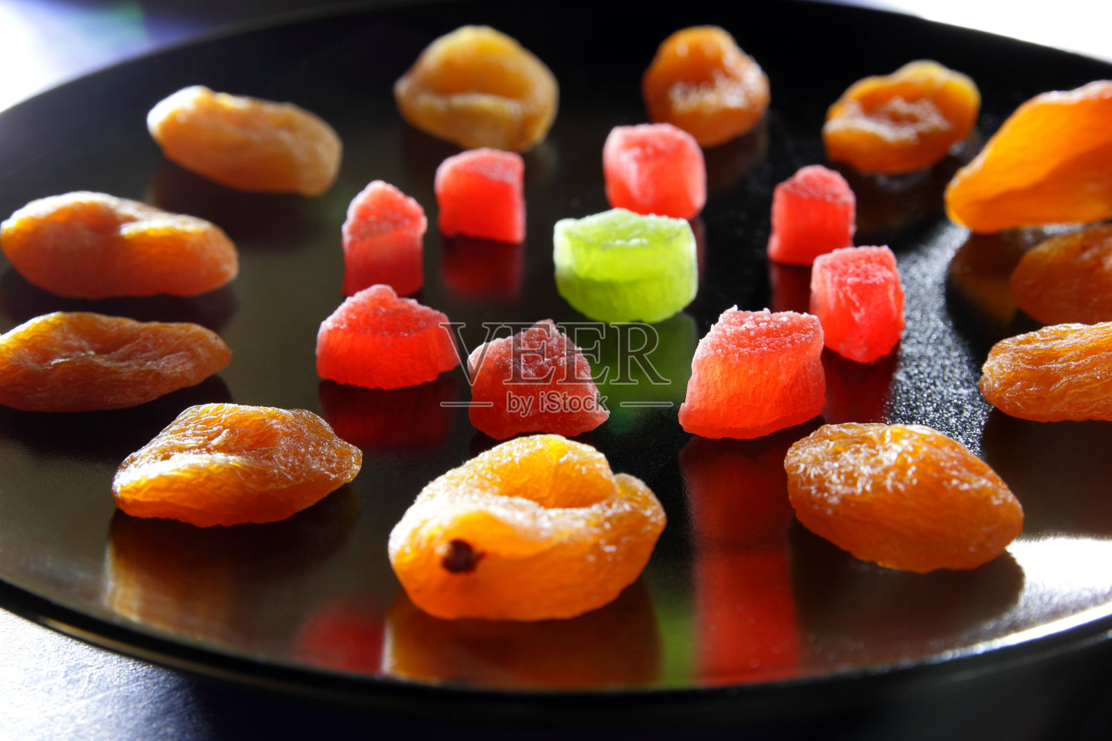 杏仁干，蜜饯水果在一个黑色的盘子里，在深蓝色的背景照片摄影图片