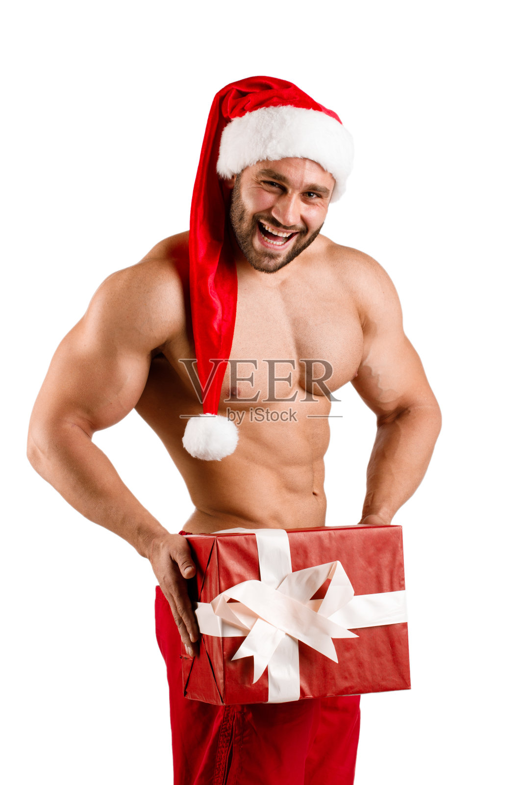 强壮的家伙戴着圣诞老人的帽子，肌肉发达的身体和大新年礼盒，孤立照片摄影图片