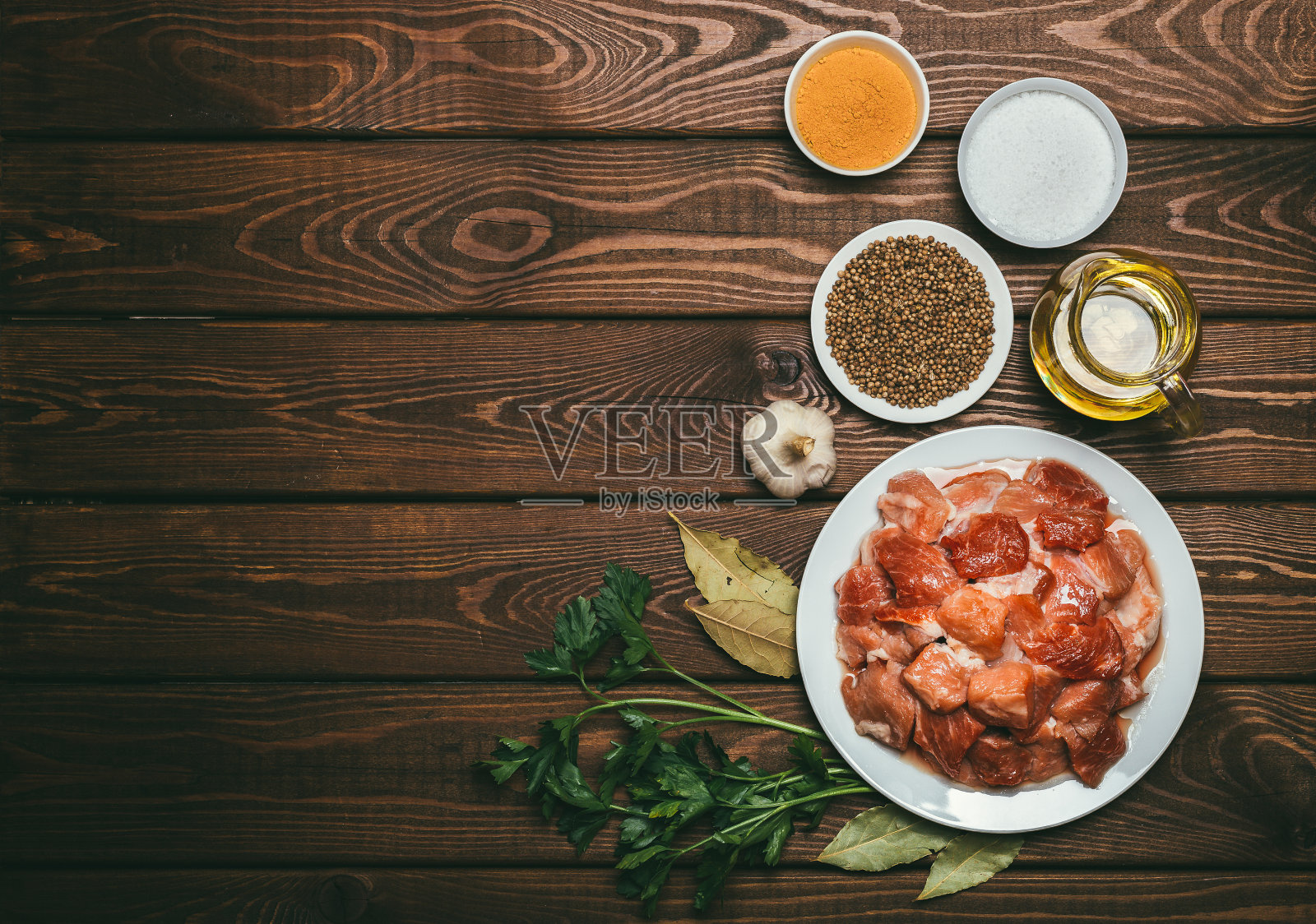烹饪材料:生肉片，油，香料，大蒜，月桂叶和欧芹照片摄影图片