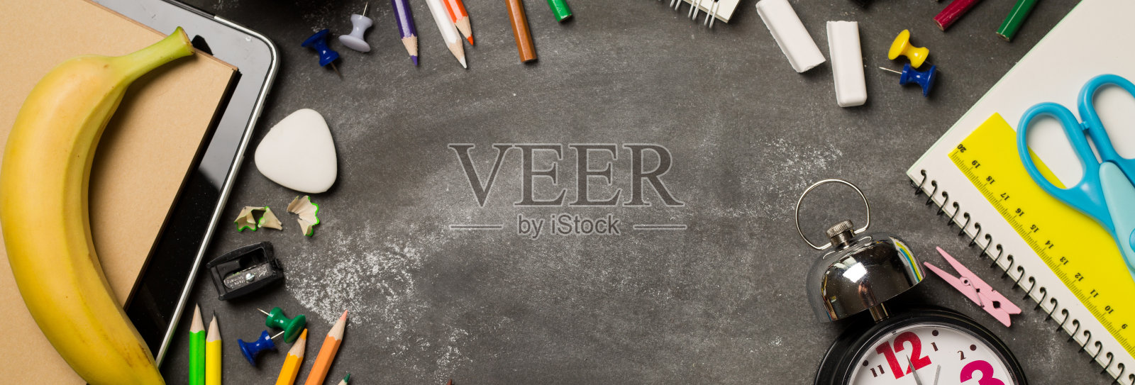 回到学校的概念与时钟彩色粉笔，苹果笔记本在黑板的背景。副本的空间。前视图。平躺照片摄影图片