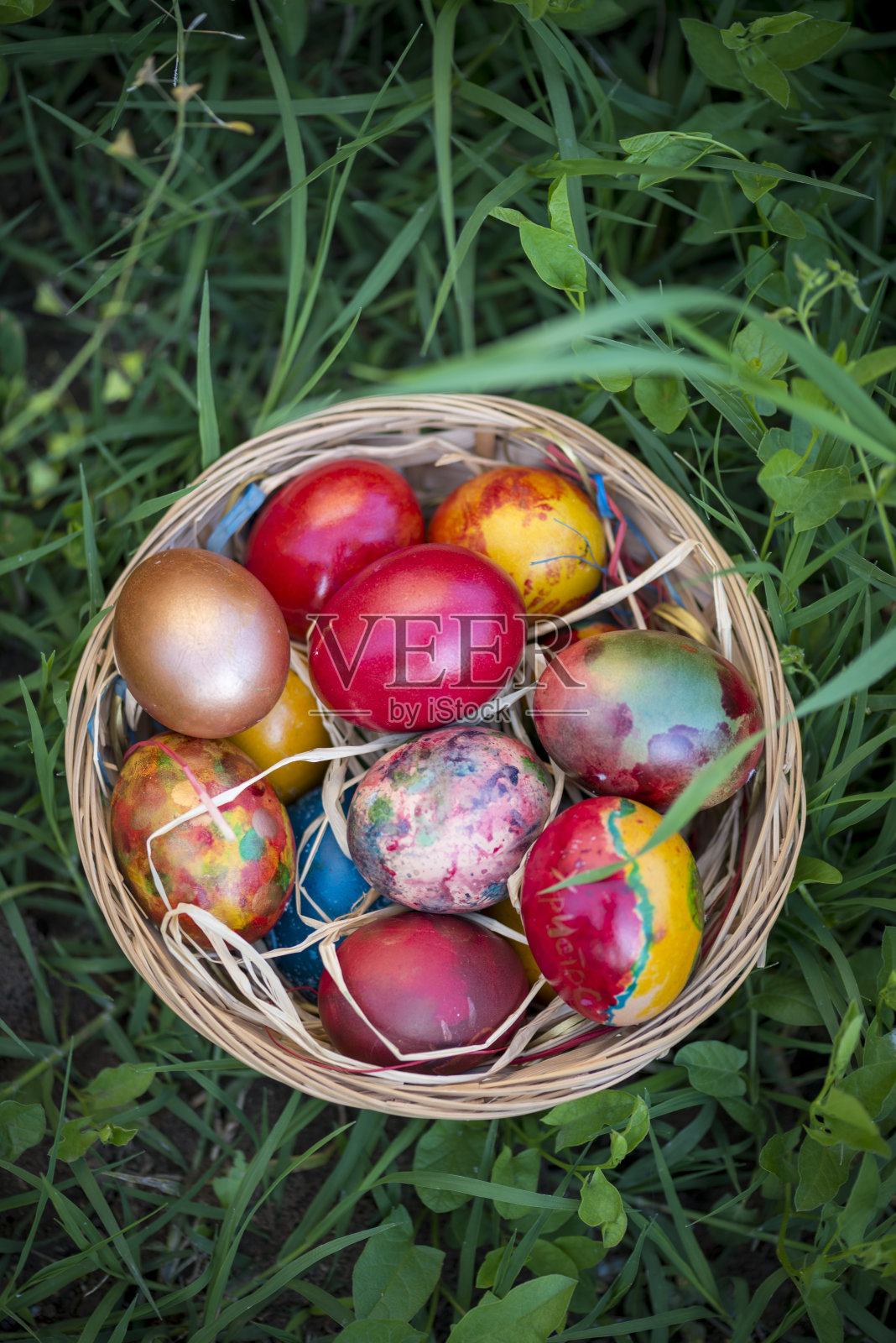 彩色的复活节彩蛋在篮子和绿色的草的背景照片摄影图片