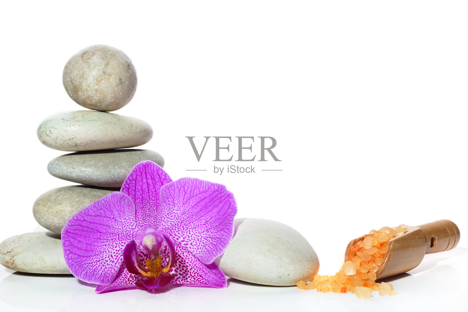 一个配有石头的水疗中心，一朵兰花和一个洒着盐的抹刀照片摄影图片