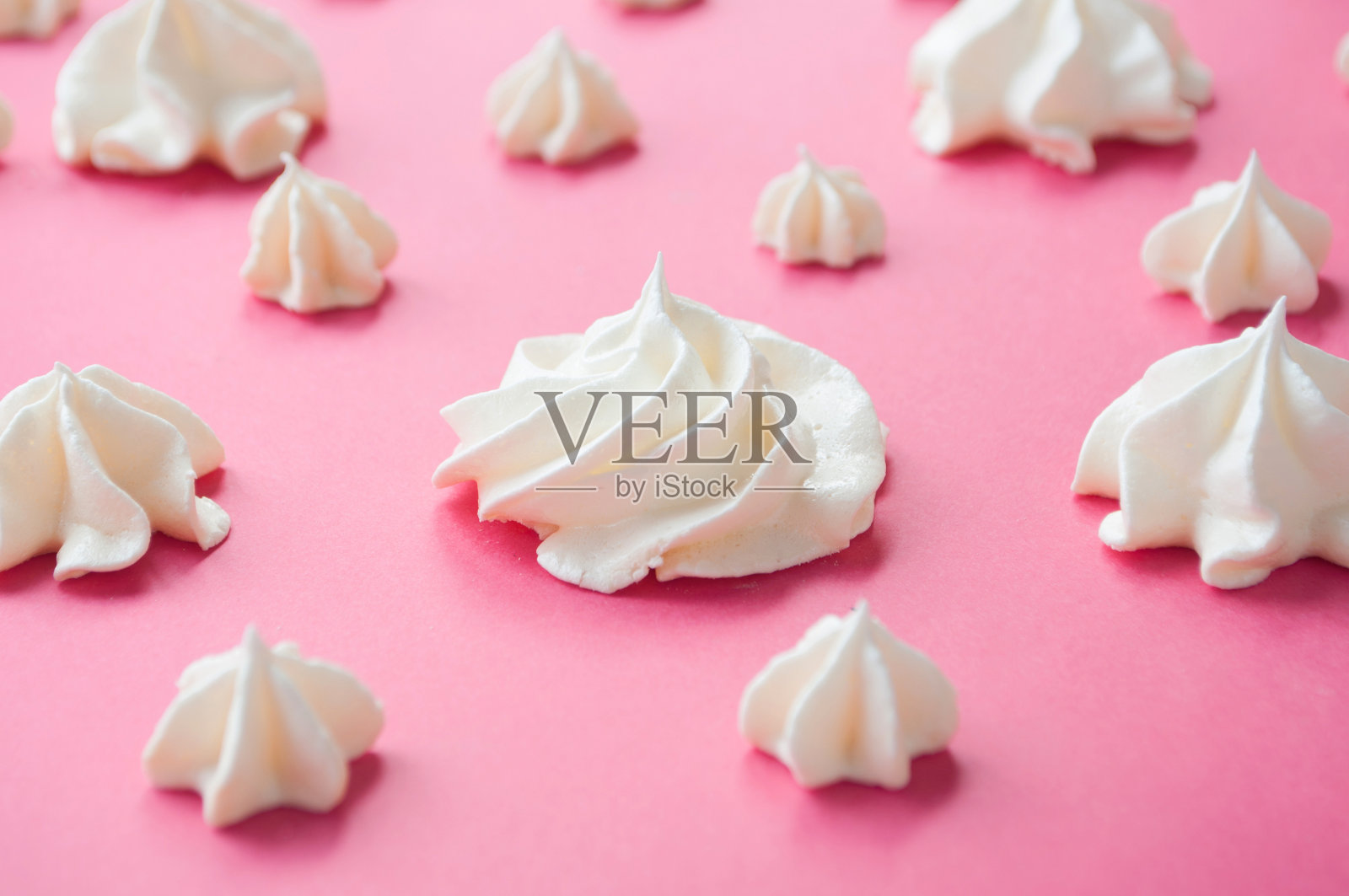 粉色背景上的白色蛋白糖霜。照片摄影图片