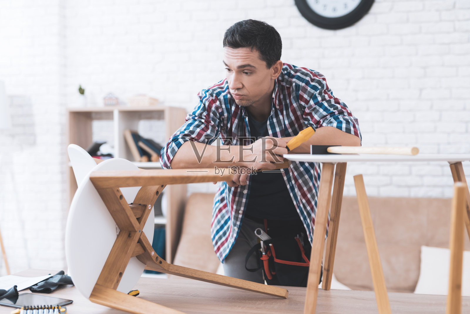 这个年轻人试着折叠他的咖啡桌和凳子。照片摄影图片