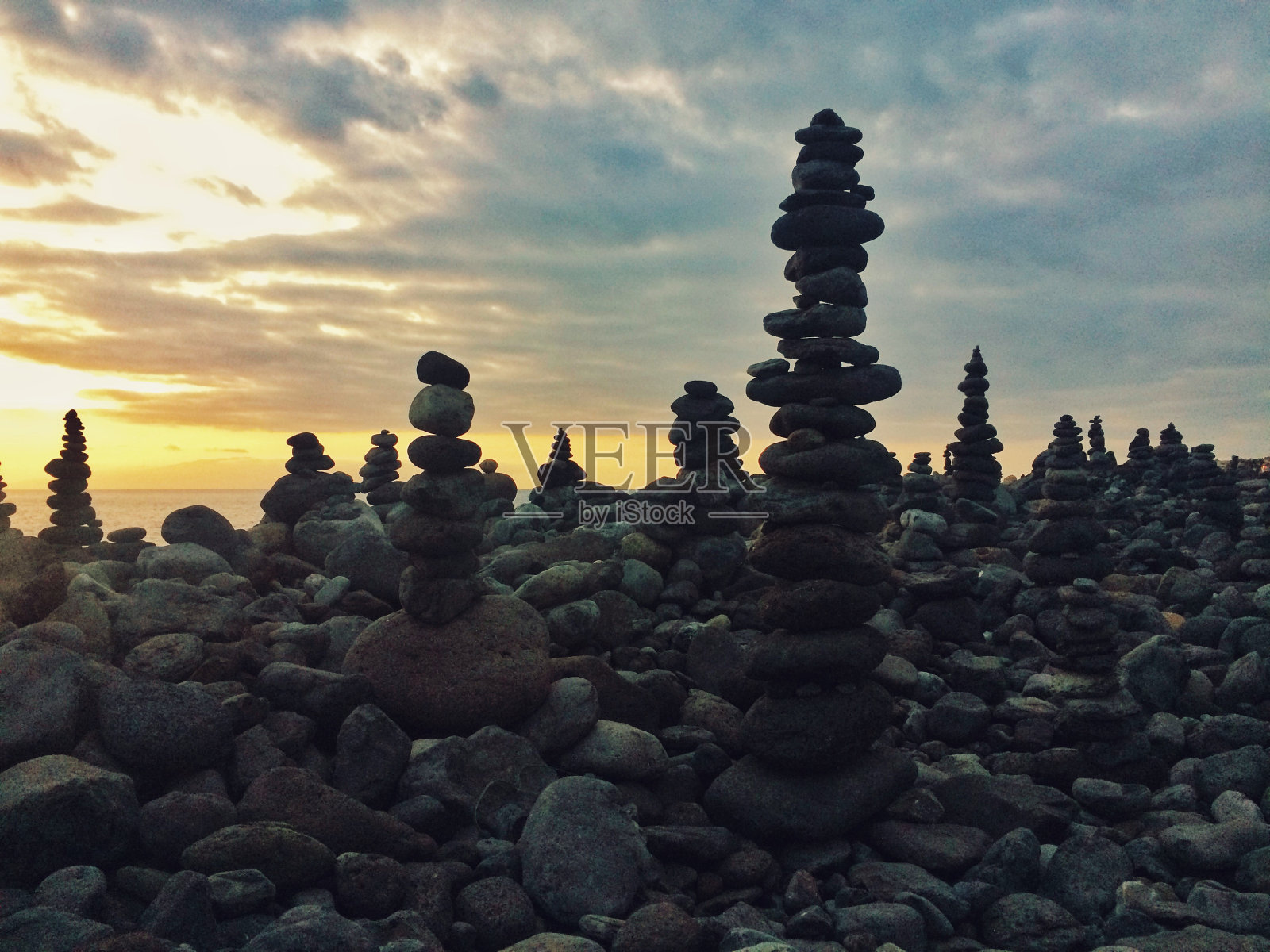 特内里费岛南部，海滩上覆盖着岩石塔，落日天空上的云朵照片摄影图片