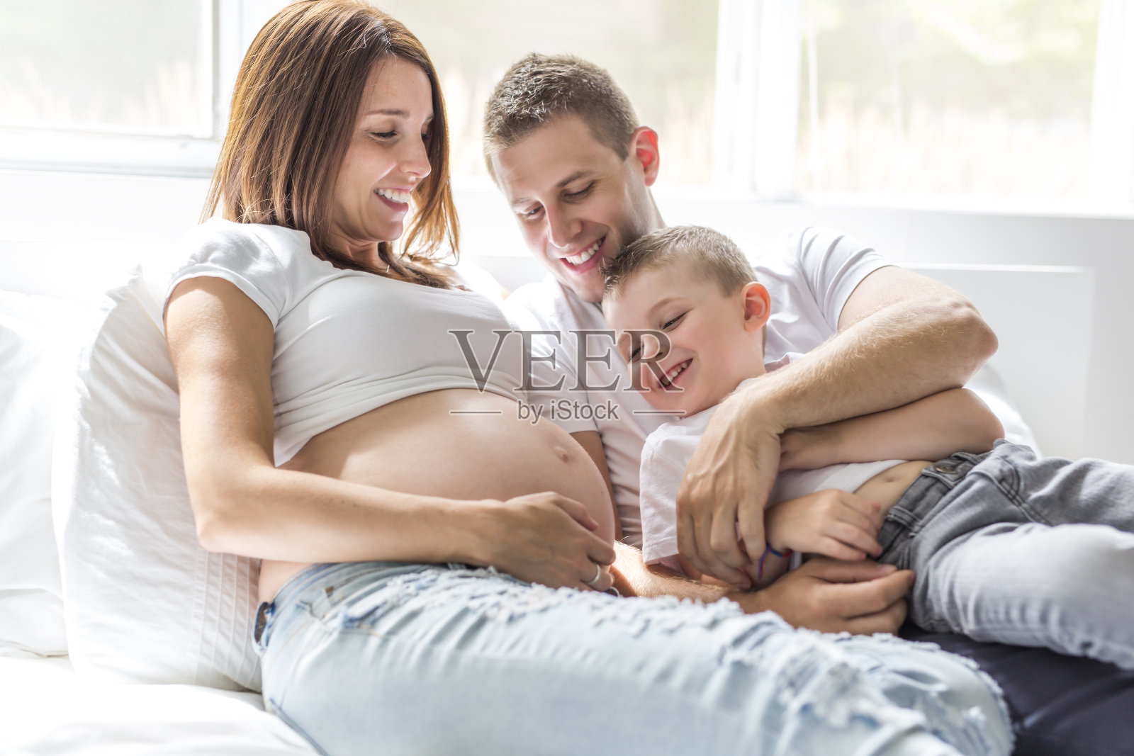 父亲，儿子和怀孕的母亲在家。美丽可爱的全家福照片摄影图片