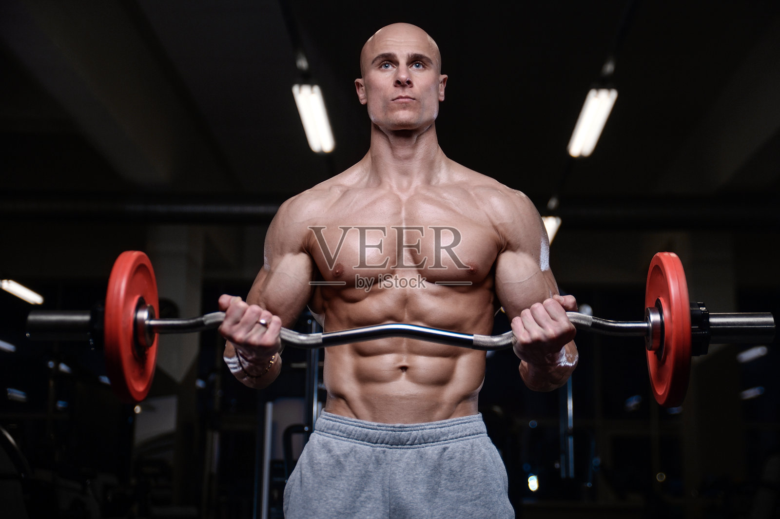 野蛮强壮的健美运动员用哑铃锻炼肌肉照片摄影图片