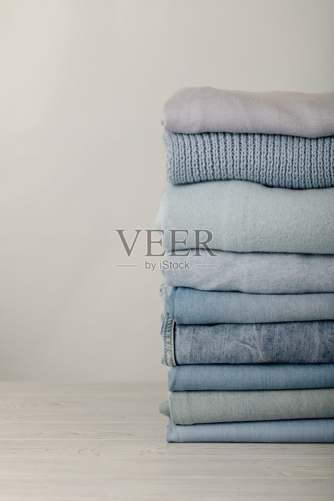 牛仔裤和针织衣服(毛衣，围巾，套头衫)蓝色，白色和灰色。照片摄影图片