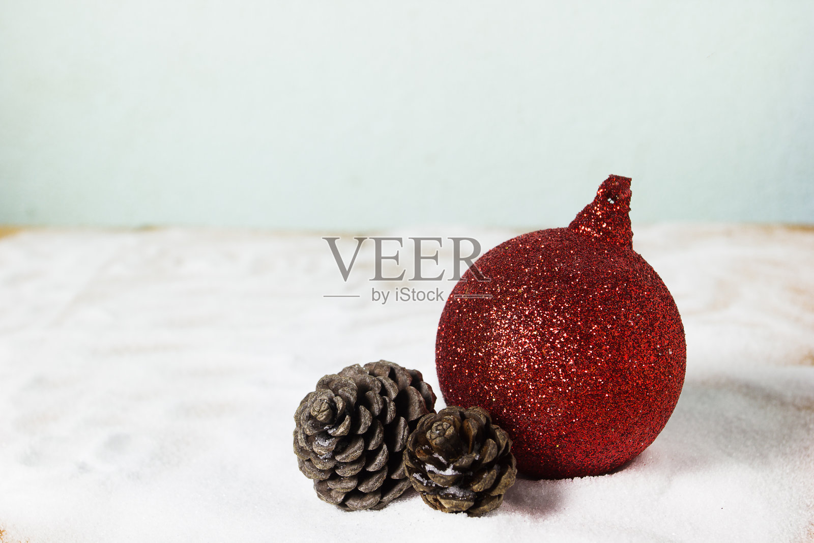 红色圣诞球和干松果在雪地背景与复制空间。圣诞背景的概念。照片摄影图片