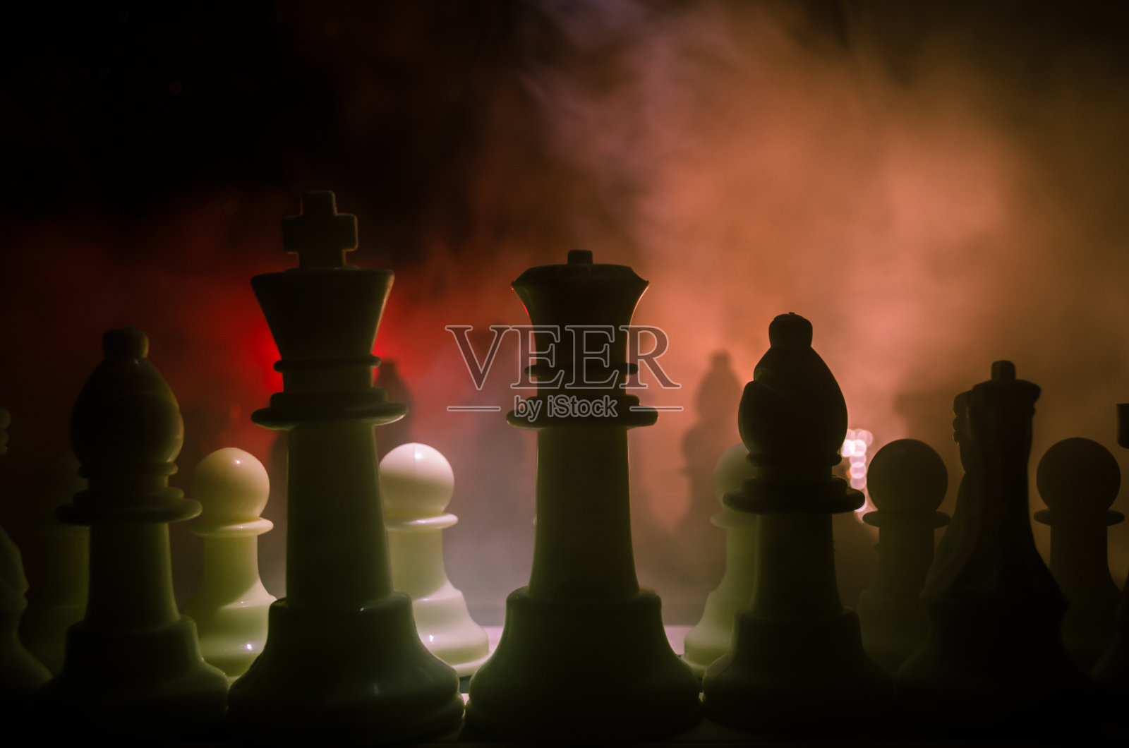 棋牌游戏的经营理念和竞争理念以及战略理念。象棋人物在烟雾缭绕的黑暗背景上。照片摄影图片