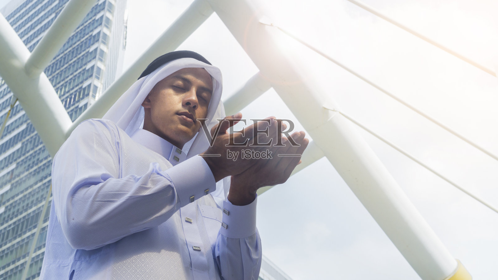 一个阿拉伯人站起来，举起双手祈祷照片摄影图片