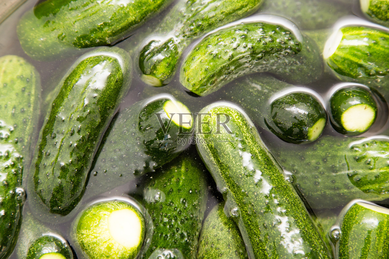 绿色黄瓜在水中洗，作为背景照片摄影图片