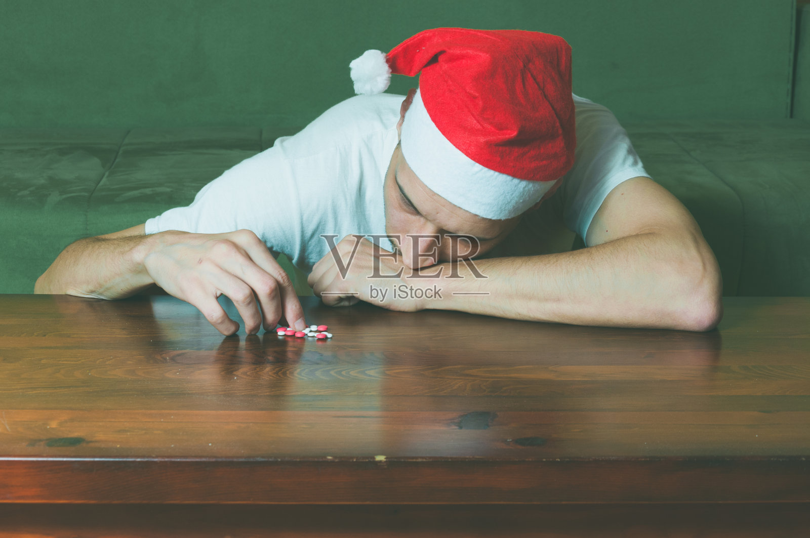 戴着圣诞老人帽的年轻男人患有自杀性抑郁症，因新年和圣诞节感到孤独悲伤照片摄影图片