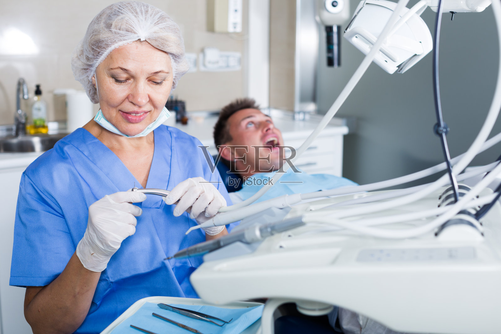 牙医在牙科诊所，病人在后面照片摄影图片