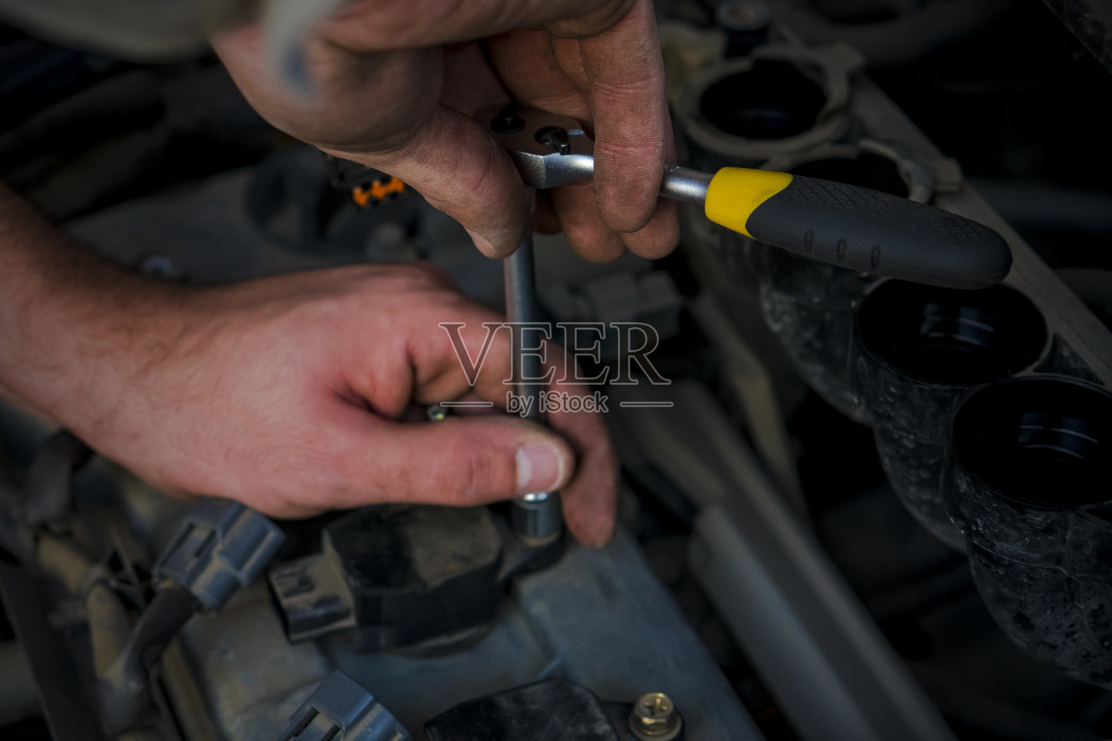 更换汽车火花塞。大师的手。照片摄影图片