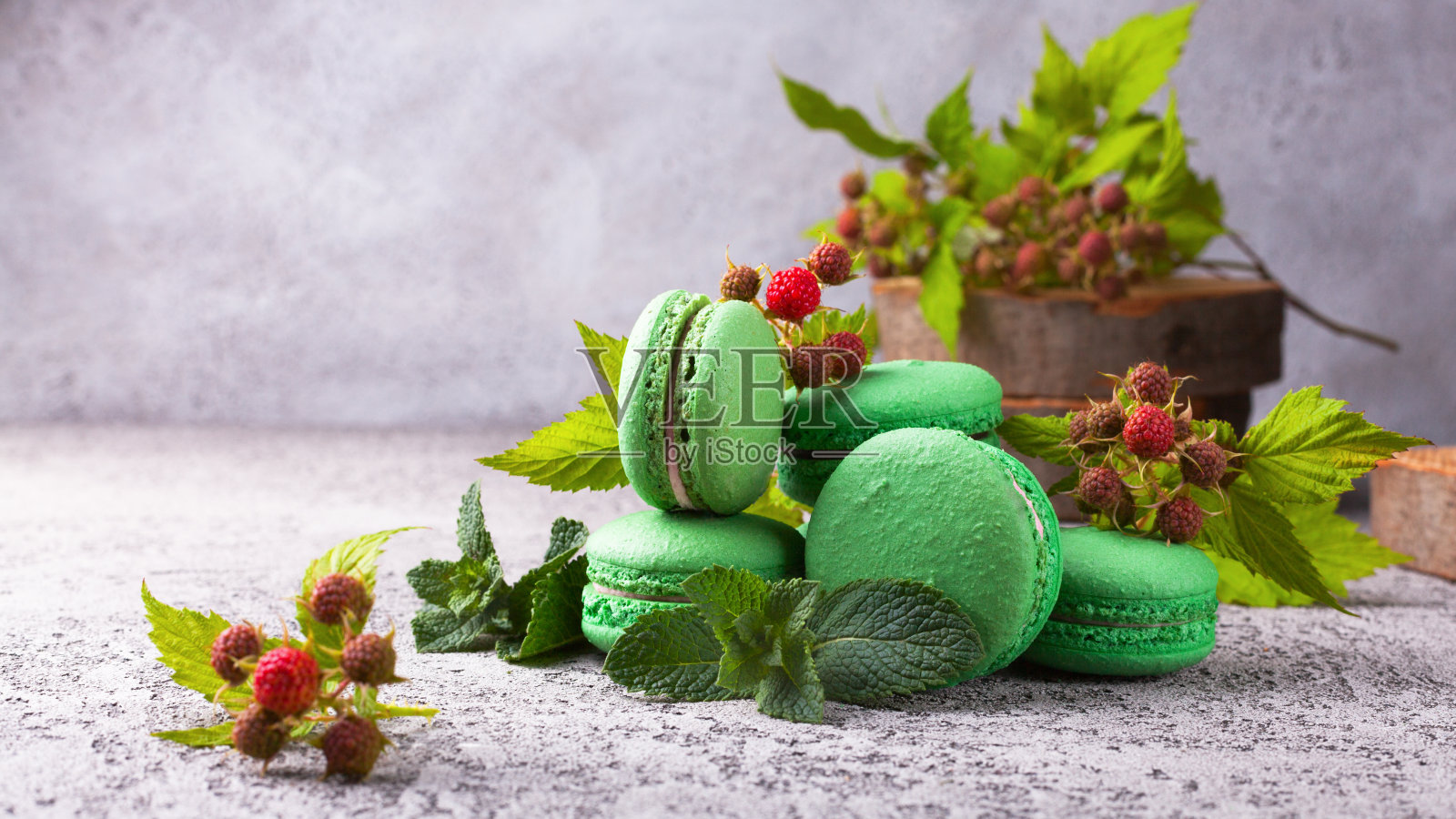 新鲜的绿色薄荷树莓法式马卡龙在浅灰色的水泥桌上。特写，复制空间，选择性聚焦。照片摄影图片