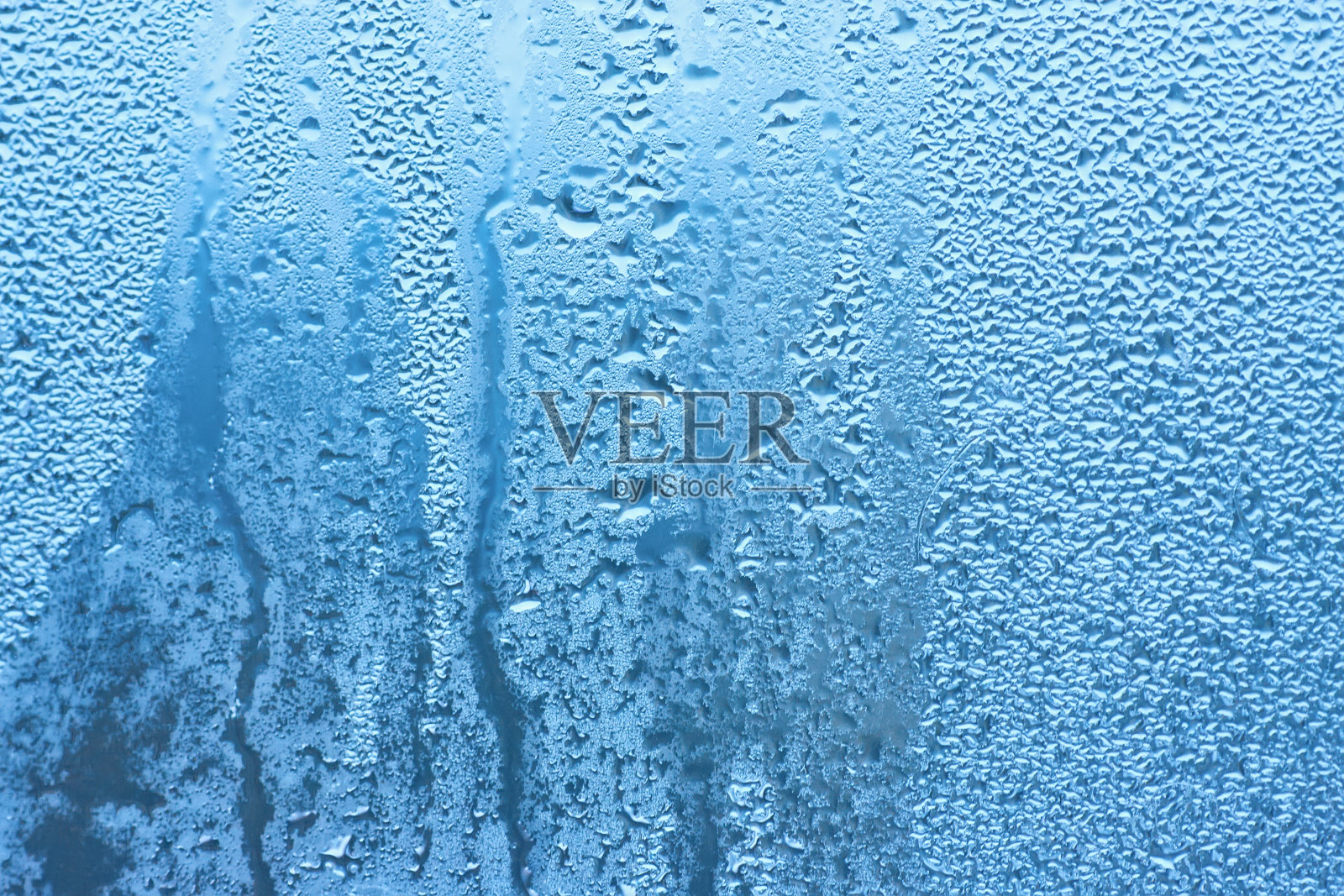 水在窗户上冒泡。蓝色背景下降照片摄影图片