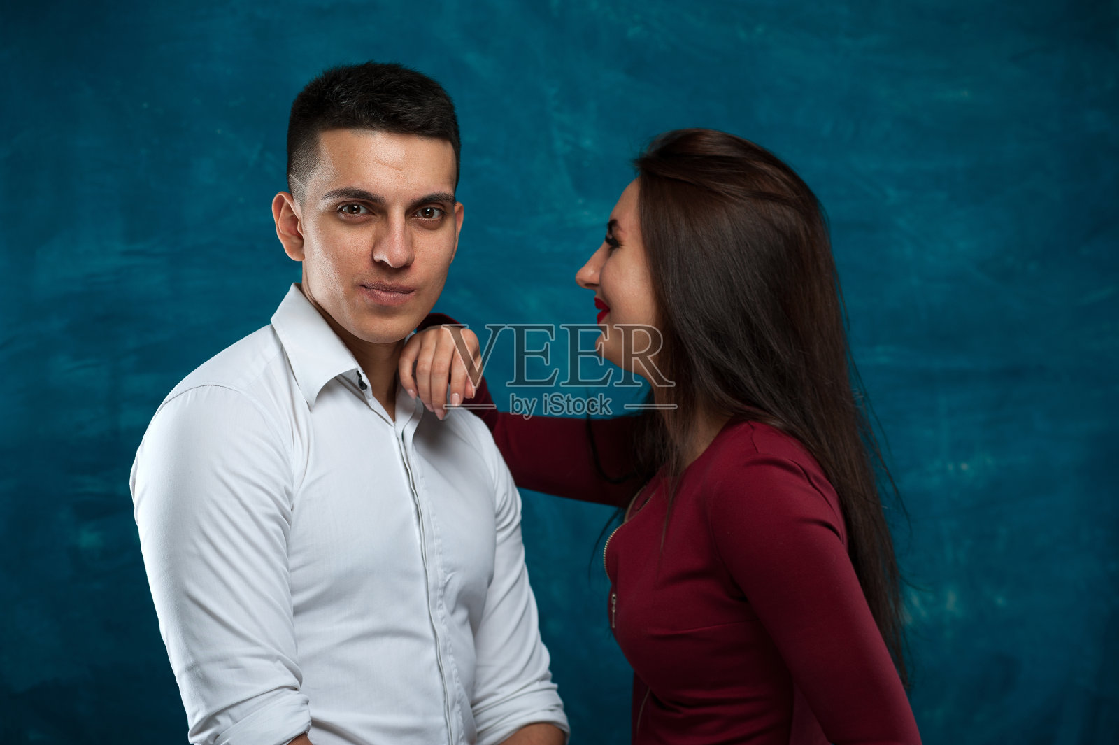 一对年轻情侣在蓝色背景下摆姿势照片摄影图片