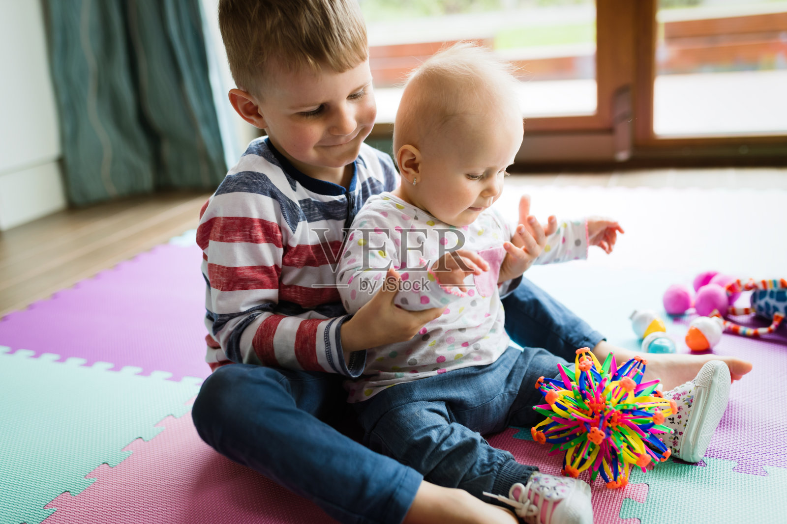 可爱的孩子们坐在地毯上玩耍照片摄影图片