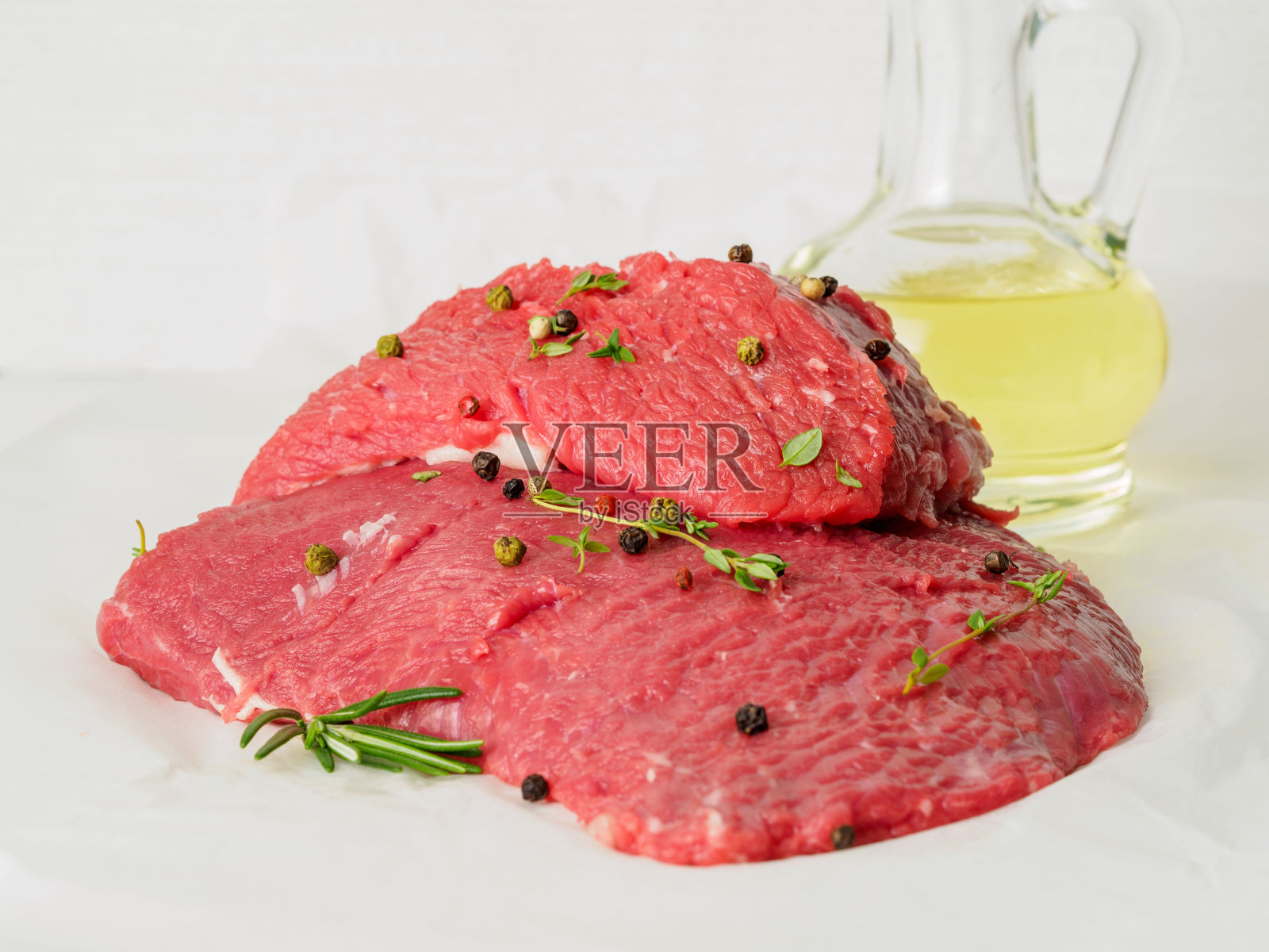 用迷迭香、胡椒和橄榄油调味的生牛肉放在白羊皮纸上，侧视图照片摄影图片