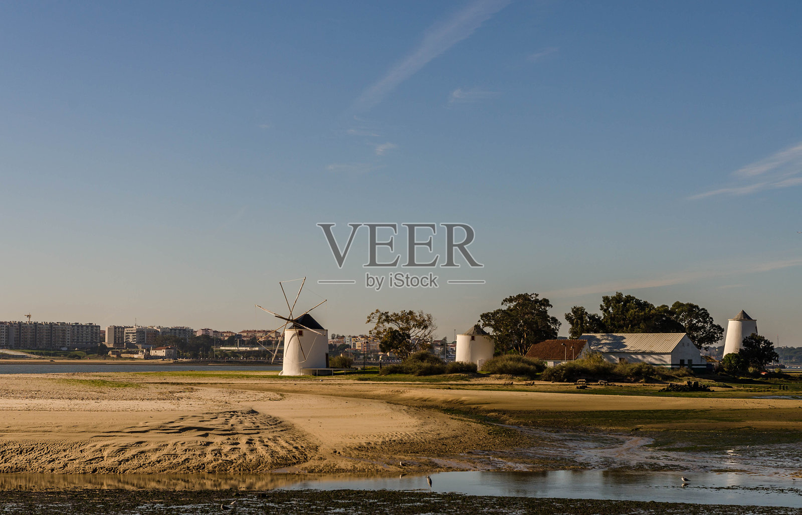 以城市天际线为背景的河流中央的风车照片摄影图片