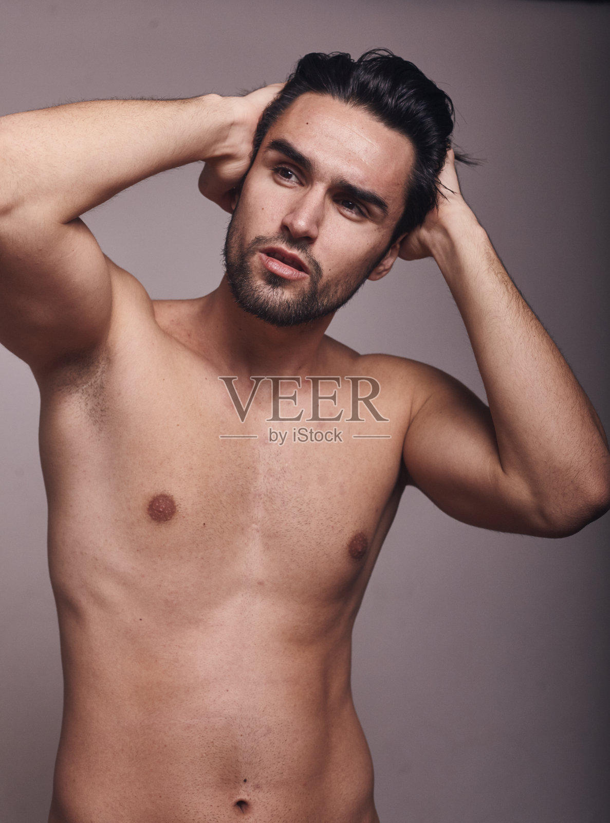 帅气性感的模特，上半身拍摄，赤膊，灰色背景，看别处，手臂抬起。照片摄影图片