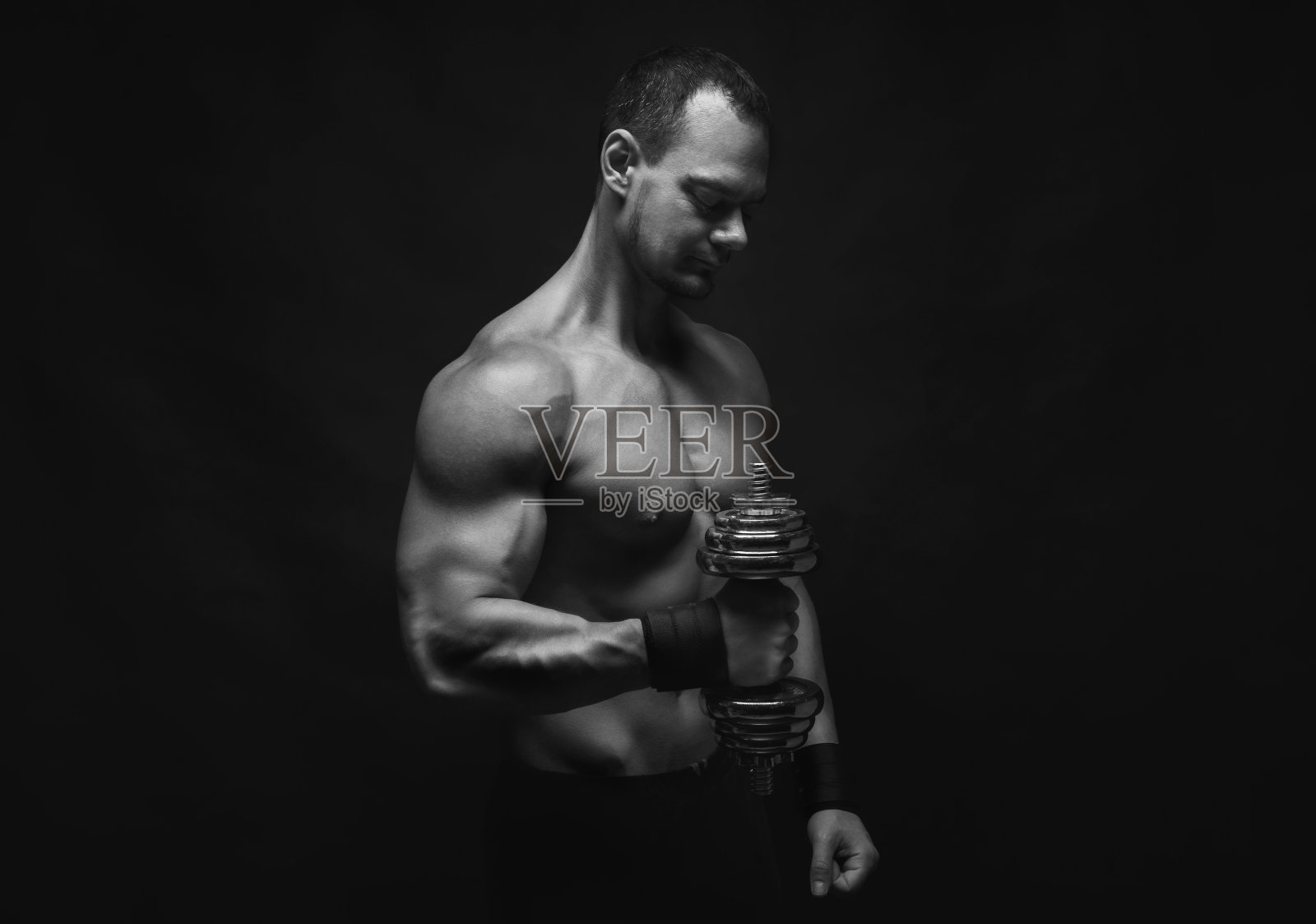强壮的运动员举着哑铃，露出赤裸的肌肉照片摄影图片