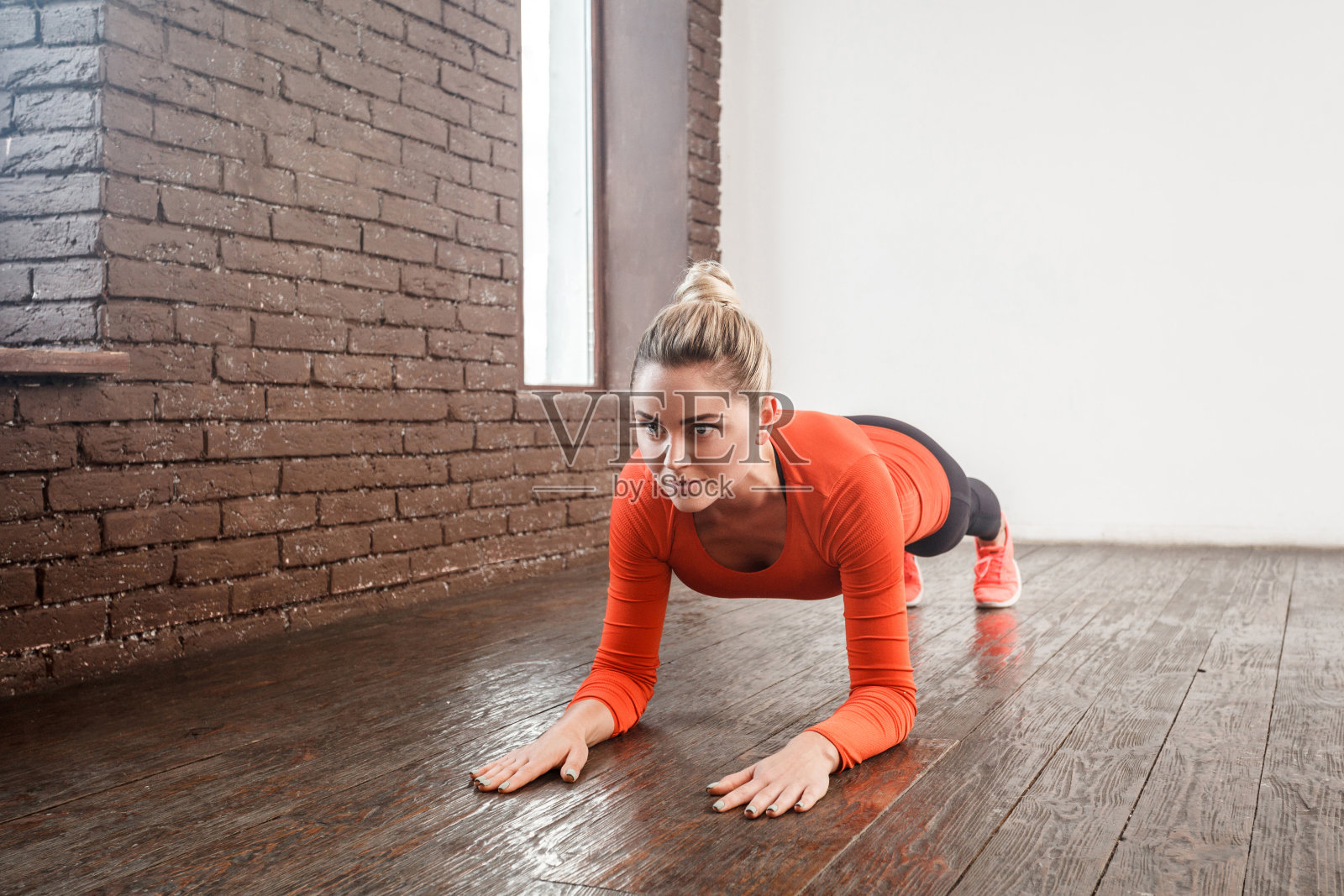 特写女子在阁楼室内做平板支撑姿势。照片摄影图片