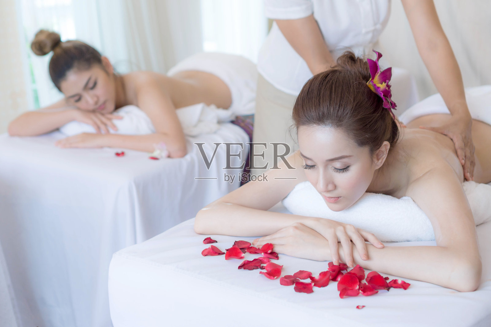 美丽和健康的女人享受在水疗沙龙的背部按摩照片摄影图片