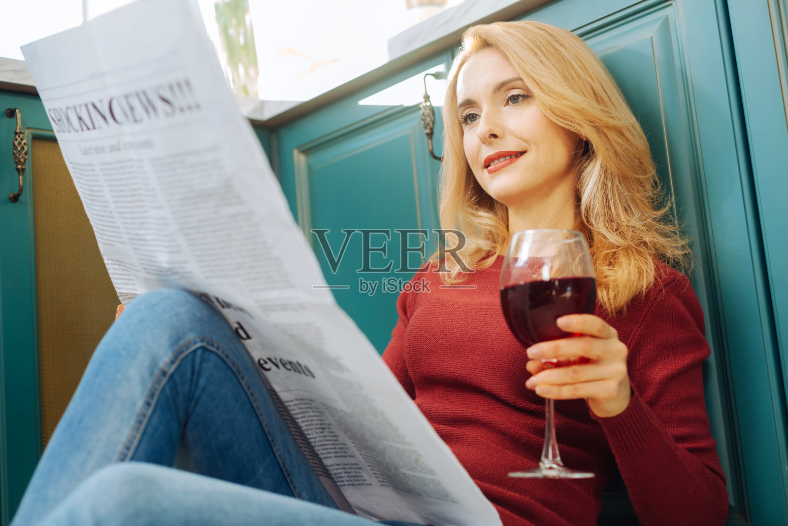 快乐的女人一边看报纸一边喝酒照片摄影图片