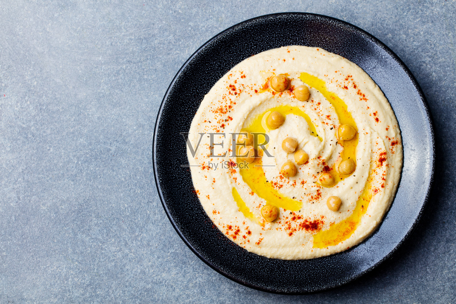 灰色石板背景黑色盘子里的鹰嘴豆泥（顶部视角，有文案空间）照片摄影图片