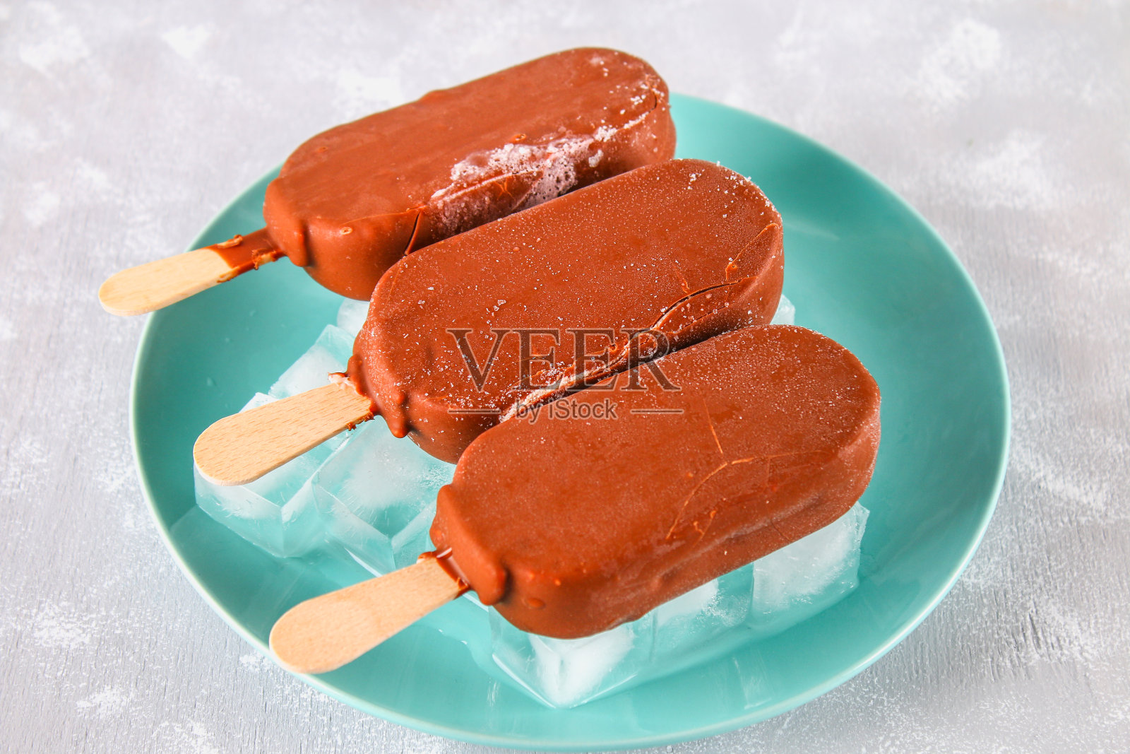 灰色的桌子上，蓝色的盘子里装着冰淇淋。爱斯基摩人。照片摄影图片