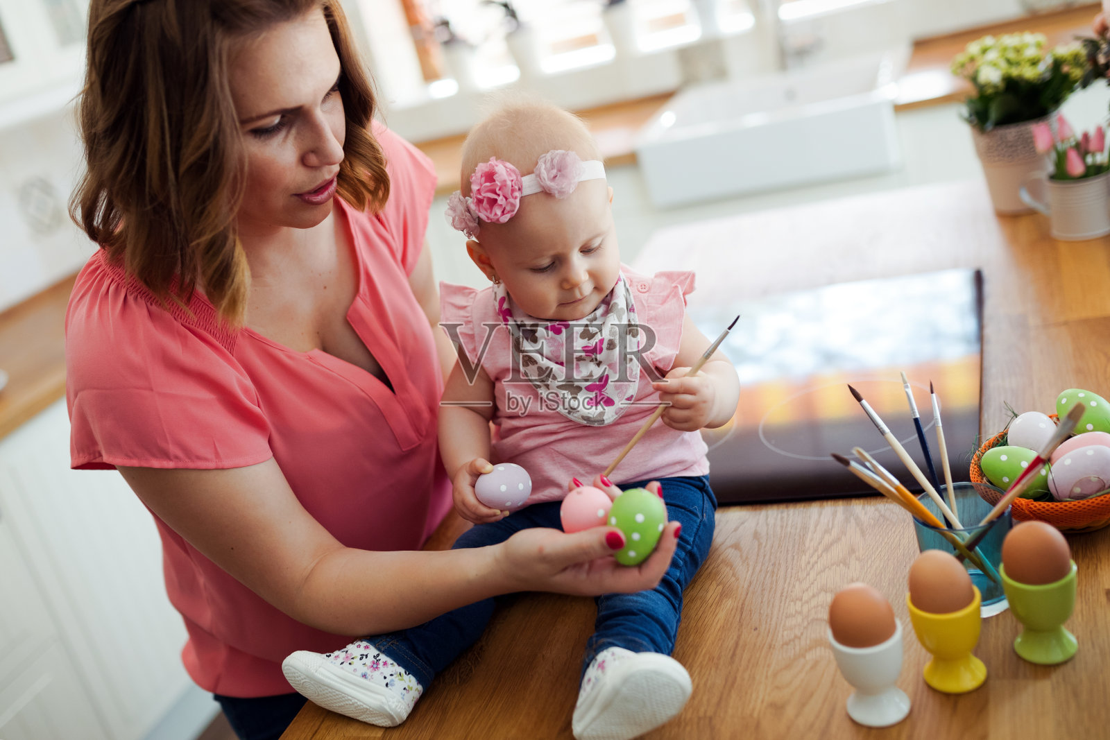 妈妈和孩子在画五颜六色的鸡蛋。照片摄影图片