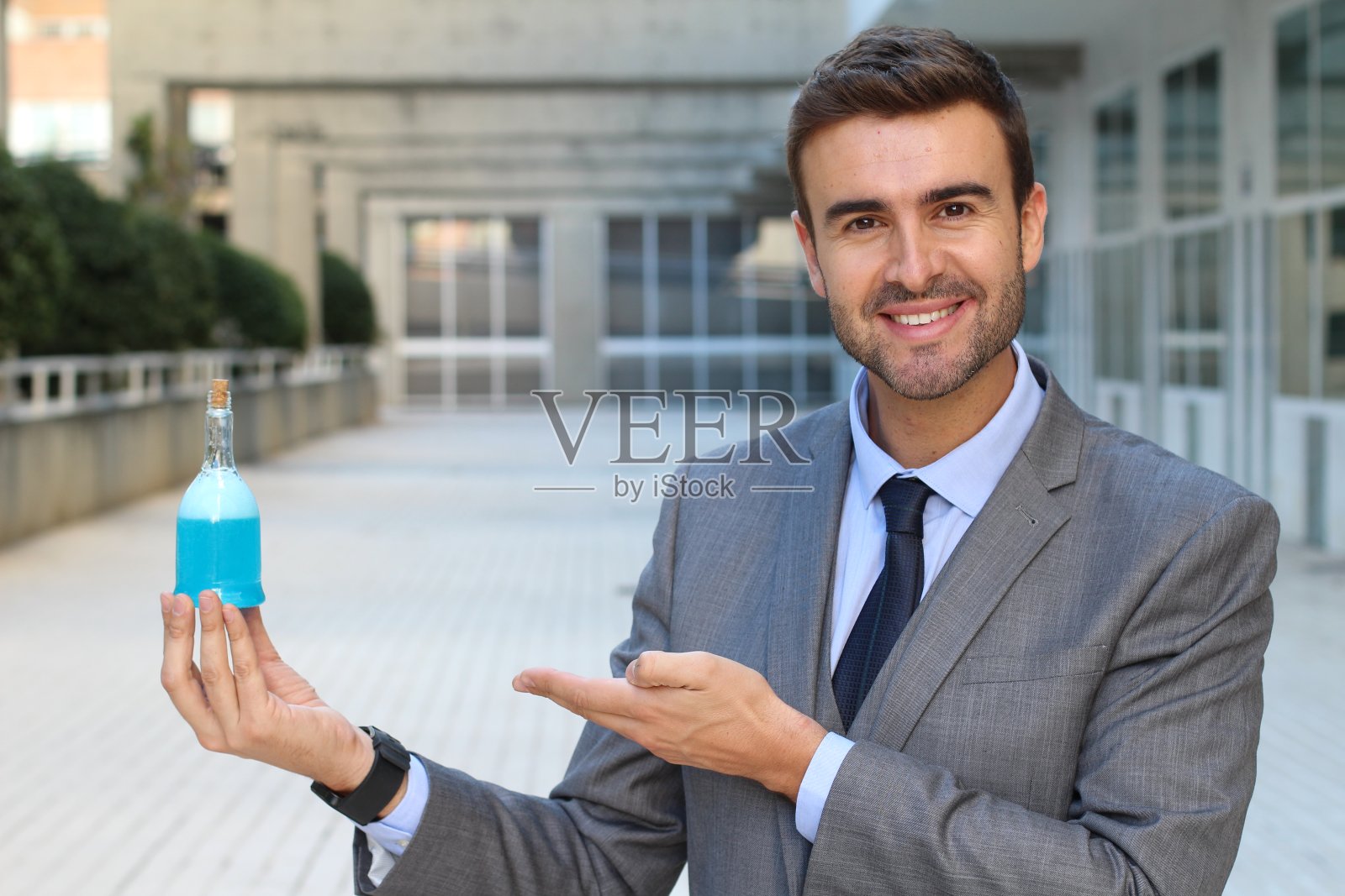 英俊的商人拿着一瓶药水照片摄影图片