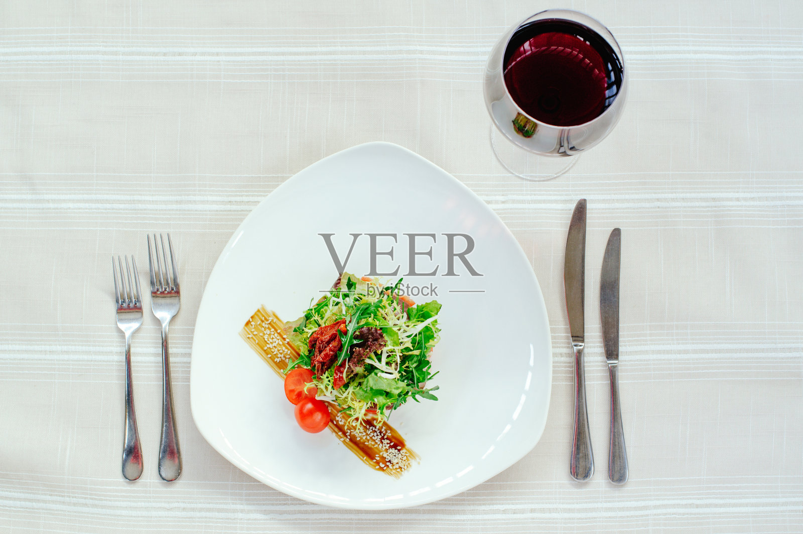 精致的沙拉米格达尔火鸡混合在一个白色的盘子，葡萄酒和桌子上的白色桌布照片摄影图片