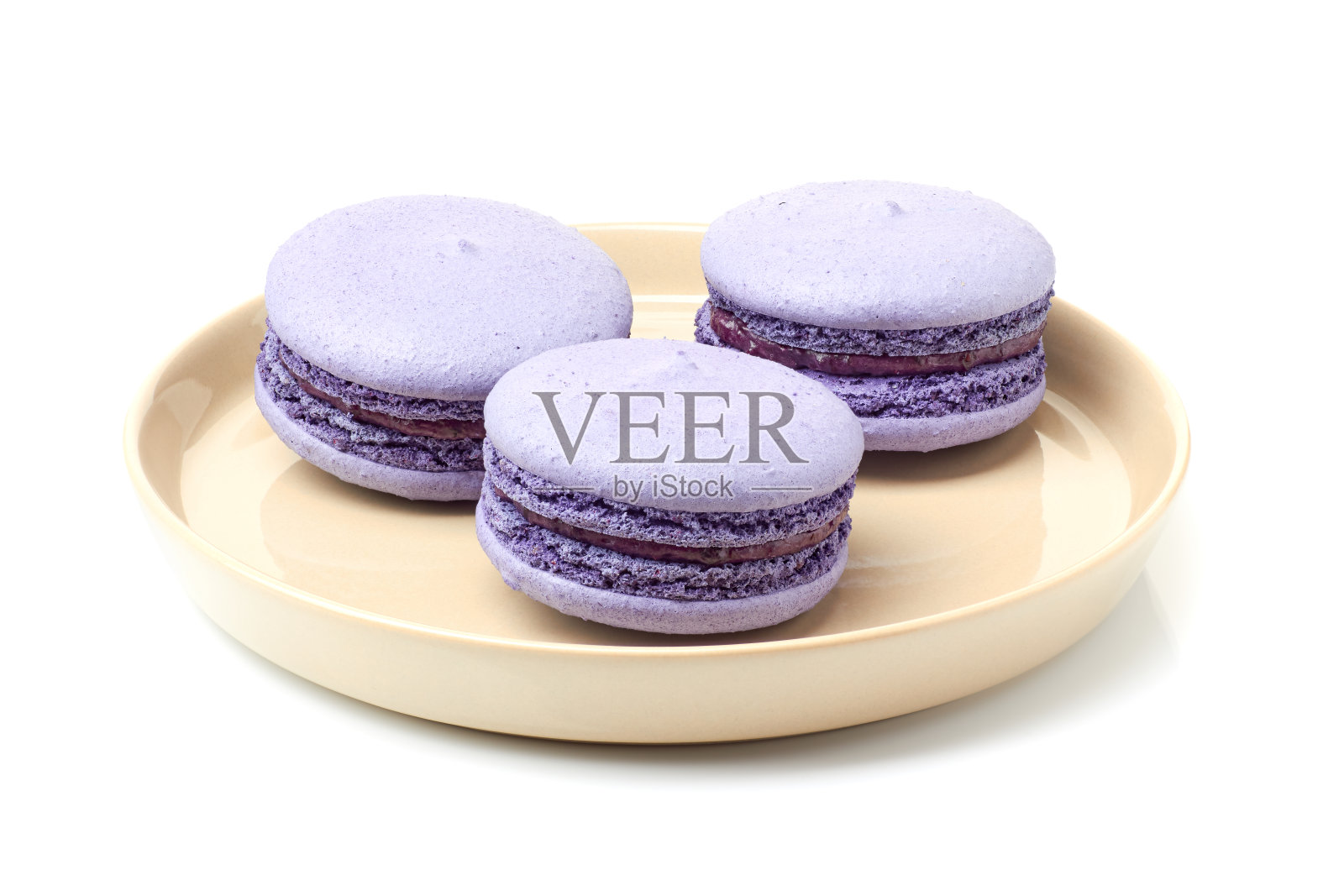 米色盘子和三个紫色的马卡龙在白色照片摄影图片
