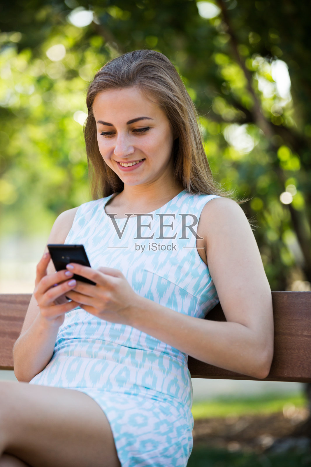 女孩坐在长椅上，在户外使用电话照片摄影图片