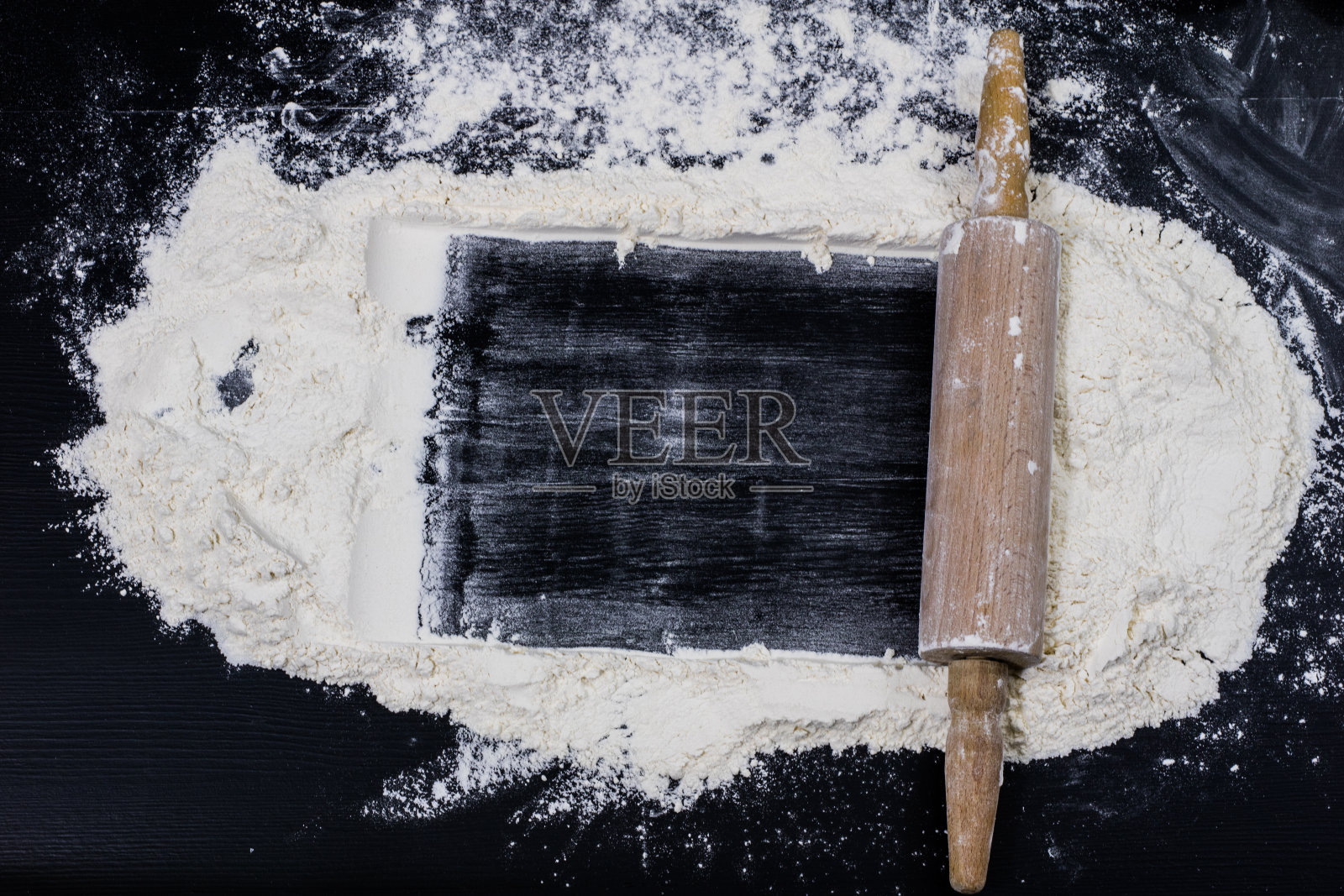 面粉和擀面棍放在厨房桌上。配件及厨房用品。黑色的桌面。照片摄影图片