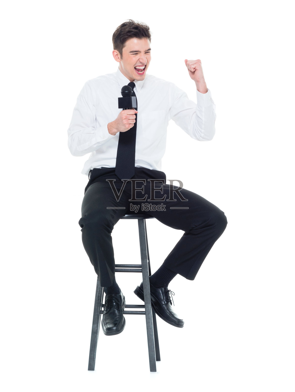 有魅力的年轻商人对着麦克风说话，坐在那里挥舞着拳头照片摄影图片