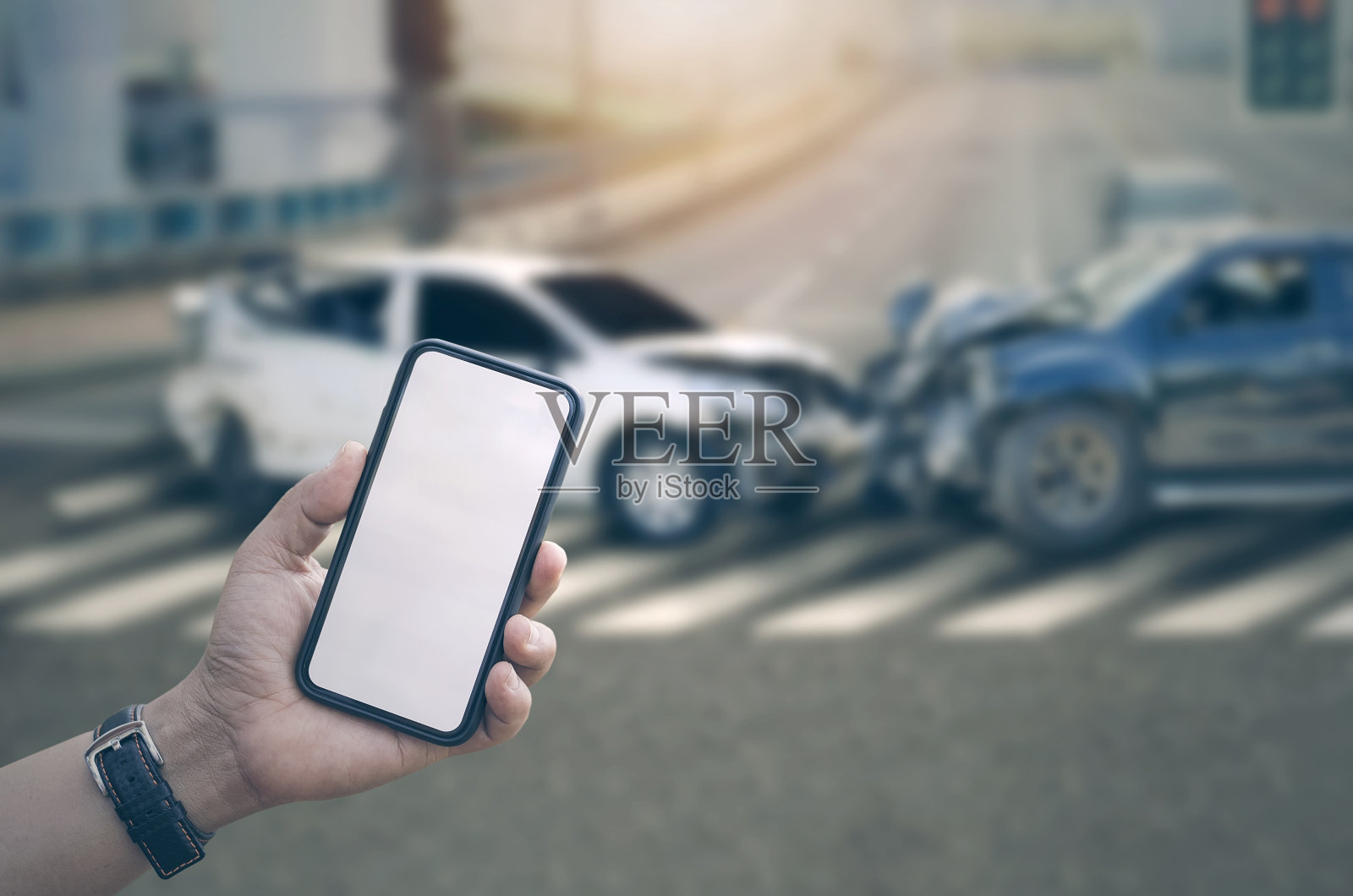 一名男子手持智能手机，屏幕空白，车祸背景模糊照片摄影图片