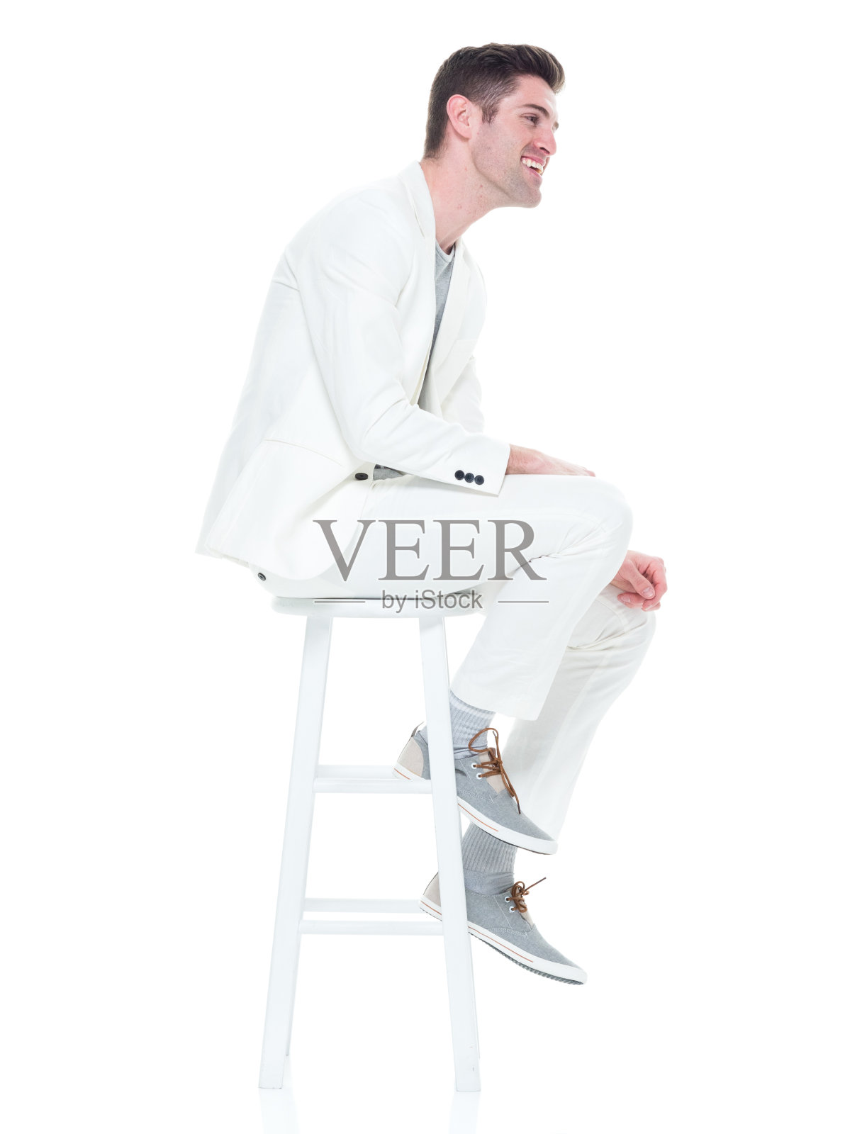 穿着白色西装坐在白色凳子上的英俊年轻人照片摄影图片