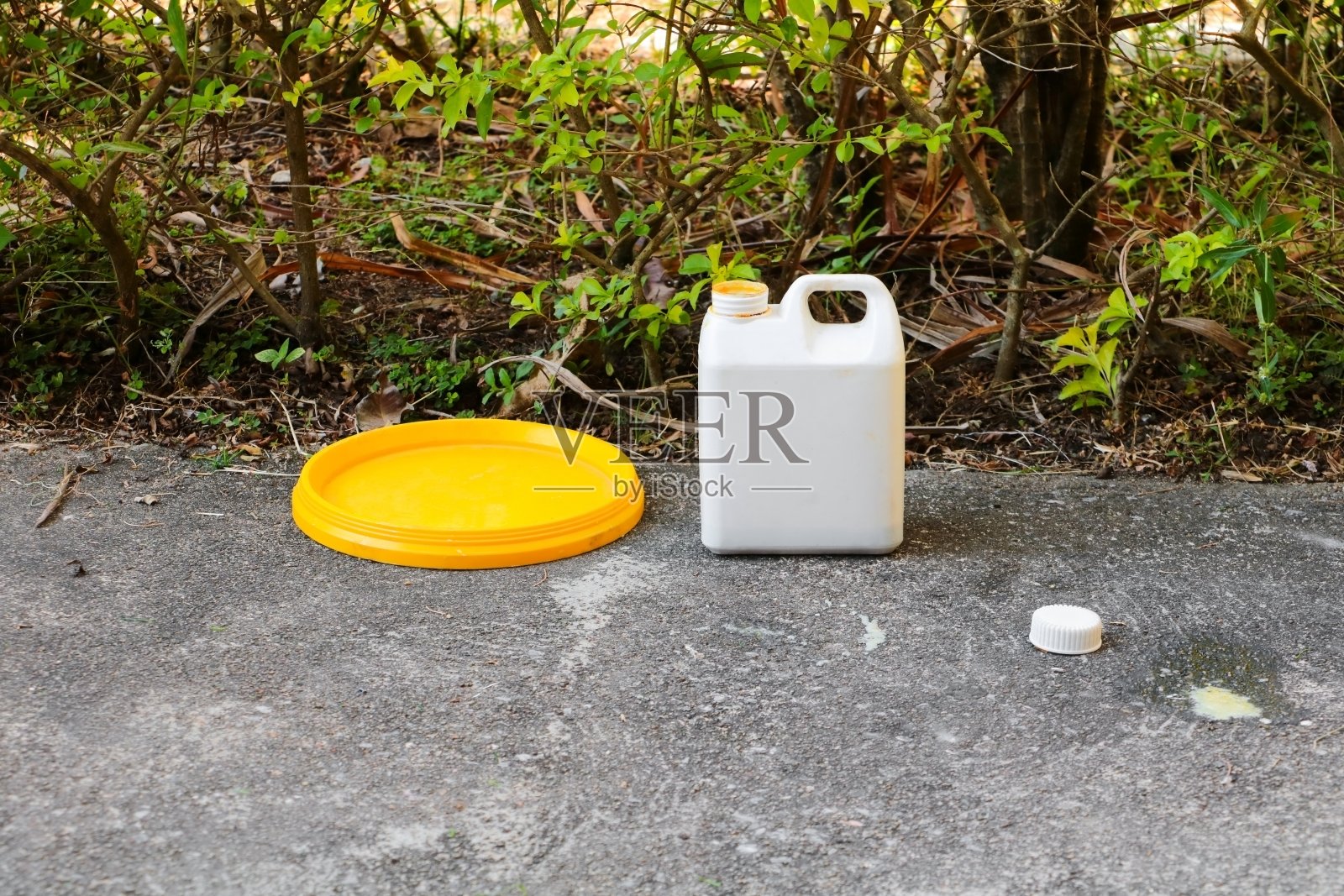 水泥地板上的白色塑料加仑油，用于颜色组合照片摄影图片