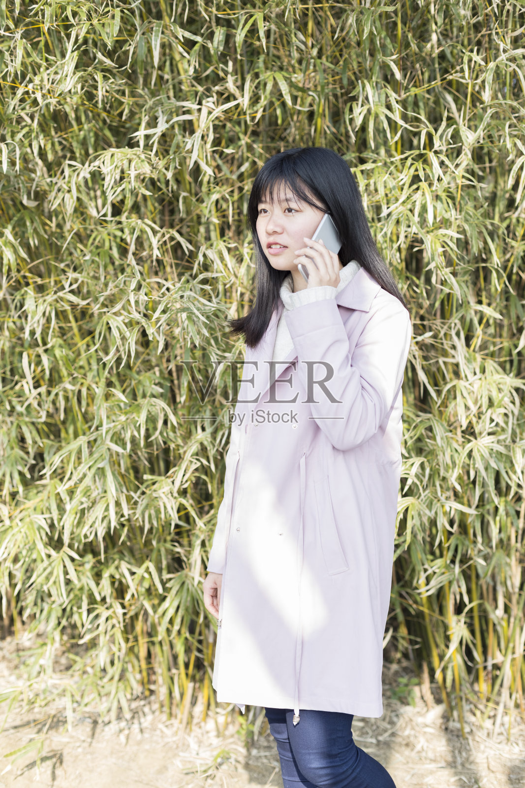 女人用手机对着茂盛的树叶照片摄影图片