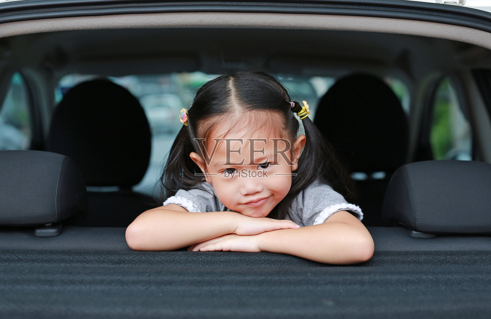 亚洲小女孩的微笑看着相机从汽车的掀背门。照片摄影图片