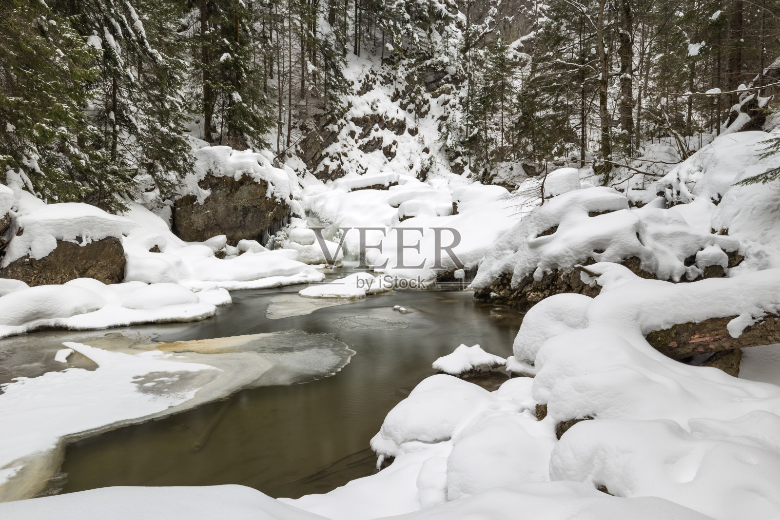 令人惊叹的冬季景观，冰雪覆盖的河流上的石头和小瀑布照片摄影图片