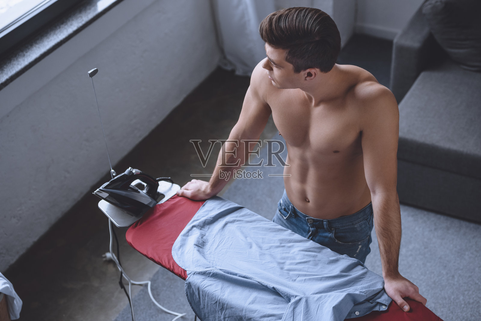 高角度的诱人的赤膊男子站在熨衣板附近照片摄影图片